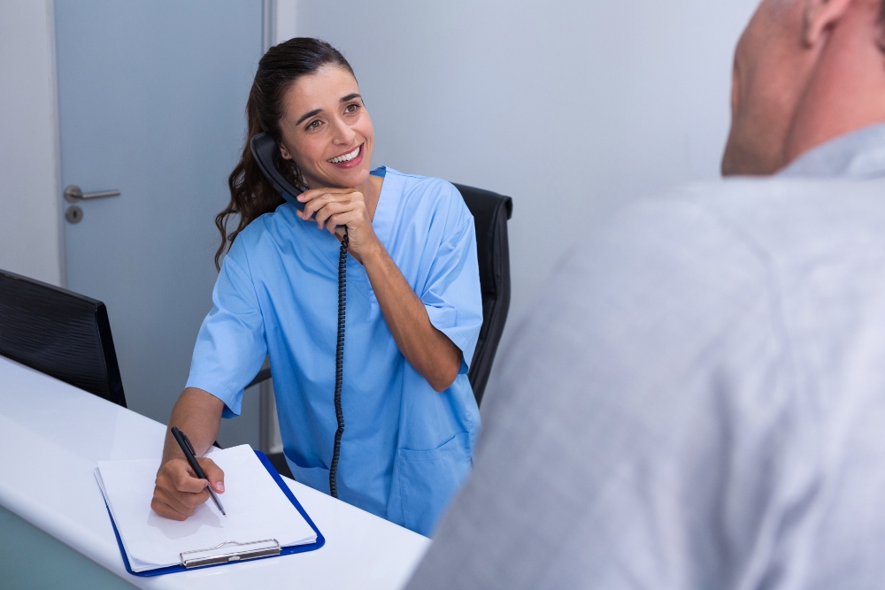 Female dentist answers the phone at the front desk of her dental practice